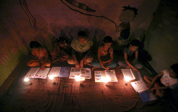 Muslim girls study in the light of candles inside a madrasa or religious school during power-cut in Noida on the outskirts of New Delhi