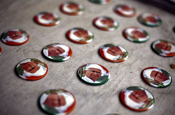 Badges with portraits of activist Anna Hazare are displayed for sale