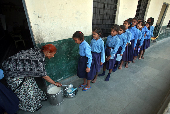 Children stand in line to collect their free mid-day meal