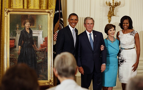 Former US President George W Bush stands next to U.S. President Barack Obama while former first lady Laura Bush stands next to first lady Michelle Obama during the unveiling of their official White House portraits in the East Room of the White House in Washington