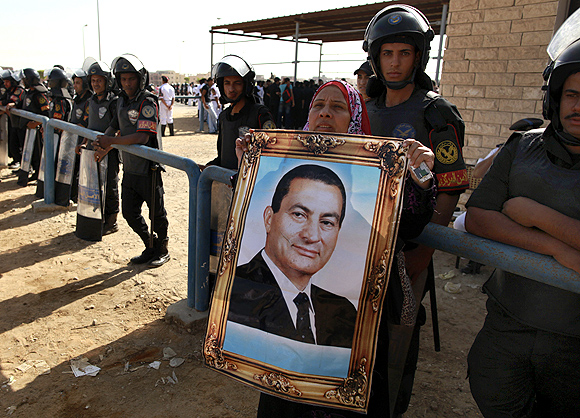 An Egyptian woman holds a picture of former president Hosni Mubarak outside the police academy where he was sentenced to life imprisonment on Saturday
