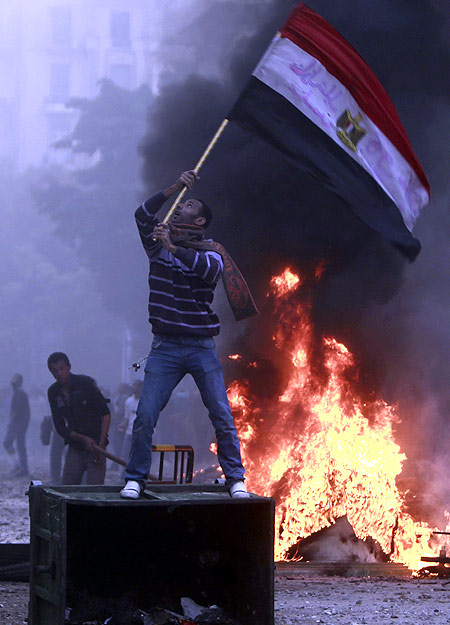 A protester waves an Egyptian flag during clashes with army soldiers at the cabinet near Tahrir Square in Cairo