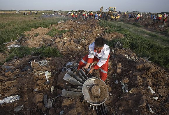 A Red Crescent volunteer moves the fan blades of an engine from a Tupolev Tu-154 passenger plane crash near Janatabad, 150 km (93 miles) west of Tehran July 15, 2009