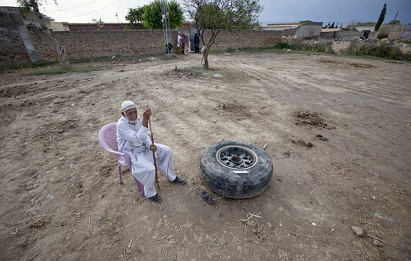 A resident sits next to a tyre of the Boeing 737 airliner operated by local airline Bhoja Air, which crashed near Islamabad April 22