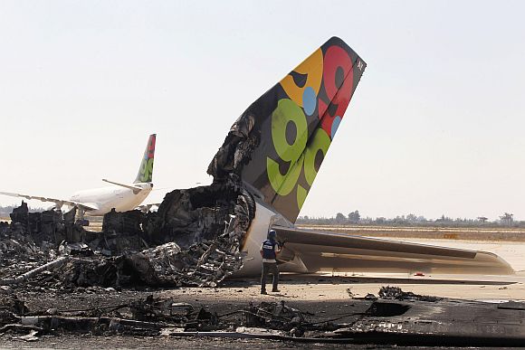 A cameraman works near a destroyed Afriqiyah Airways aircraft at the Tripoli Airport August 25, 2011