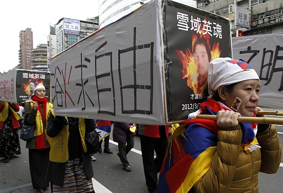 Activists carrying mock-ups of coffins to mourn for those who killed themselves in self-immolation, take part in a rally to support Tibet in Taipei