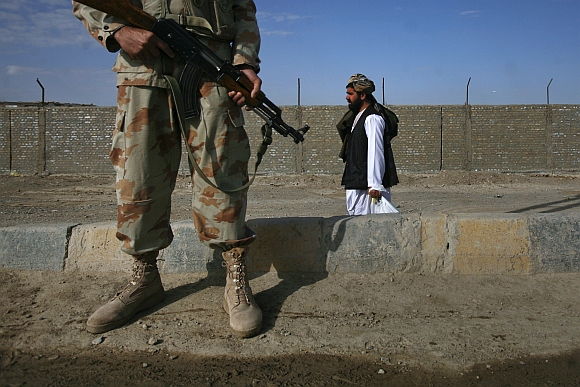 A man walks past an armed paramilitary soldier guarding the Pakistan-Afghanistan border crossing in Chaman