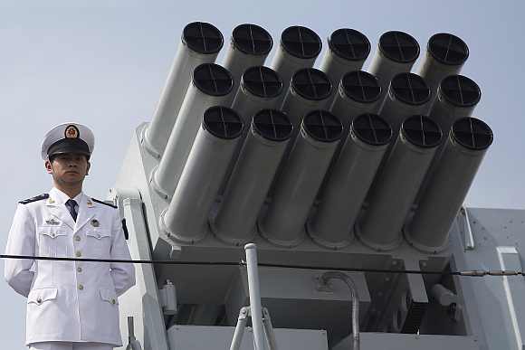 A Chinese People's Liberation Army Navy personnel stands on the deck of the Chinese naval guided missile destroyer Haikou