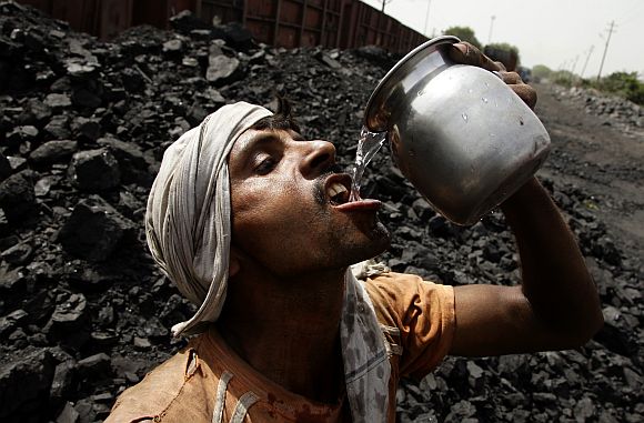 A labourer drinks water as he takes a break from loading coal onto trucks at a coal yard near Allahabad.