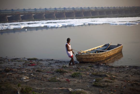 A man pulls his boat offshore in the waters of the river Yamuna in New Delhi