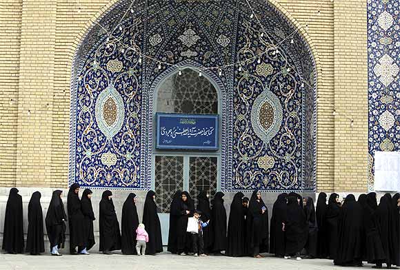 Women stand in line to cast their votes during the parliamentary election, in the court yard of the holy shrine in Qom