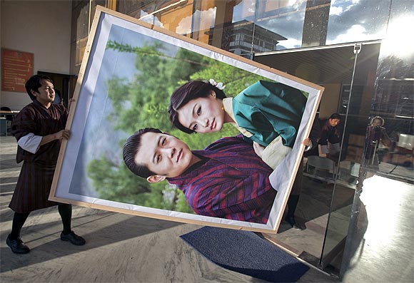 Men carry a portrait of King Jigme Khesar Namgyel Wangchuck and his fiancee Jetsun Pema to display inside an office building in Bhutan's capital Thimphu