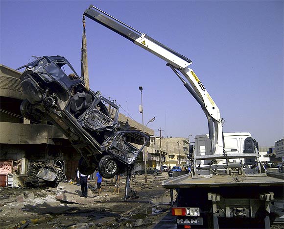 A burnt vehicle is removed from the site of a bomb attack, which killed Shi'ite pilgrims who were making their way to a religious festival, in Baghdad