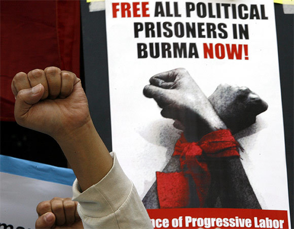 A Free Burma Coalition-Philippines protester raises a clenched fist in front of a placard during a rally in front of the Myanmar embassy in Makati's financial district of Manila
