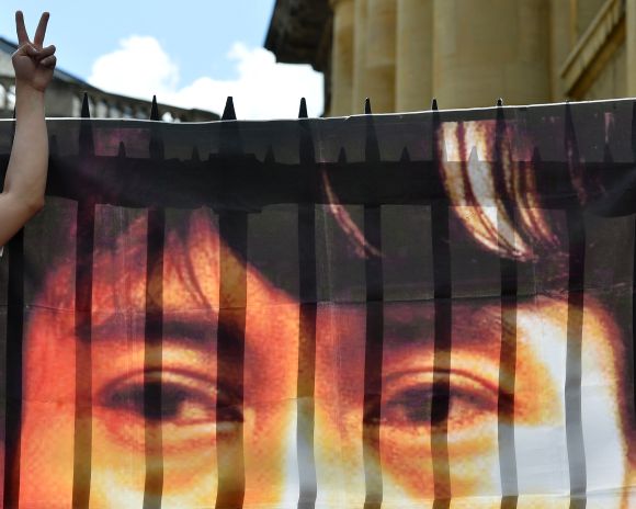 A supporter Aung San Suu Kyi gestures next to a banner of her photograph hung at the Bodleian Library in Oxford