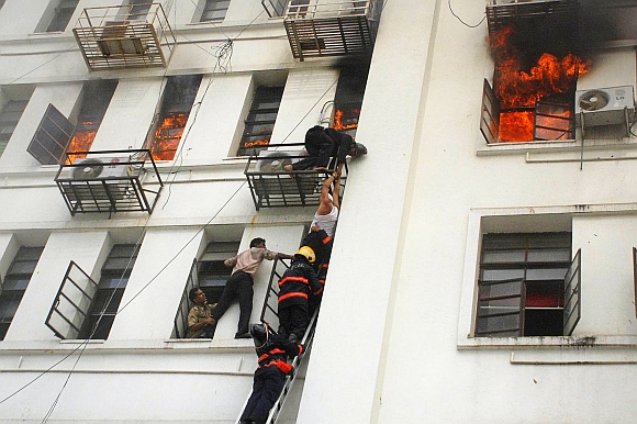 A man is rescued by firefighters from the Maharashtra state secretariat building after a fire broke out, in Mumbai June 21