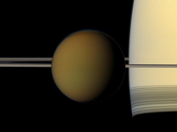 The colorful globe of Saturn's largest moon, Titan, passes in front of the planet and its rings in this true color snapshot from NASA's Cassini spacecraft.