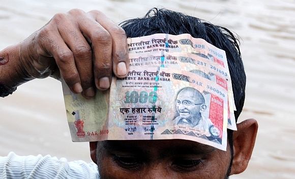 A man holds up the Rs 1,000  notes he found in the water body