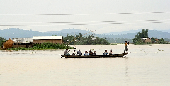 Flood victims travel through affected areas of Ashigarh village in Morigoan district