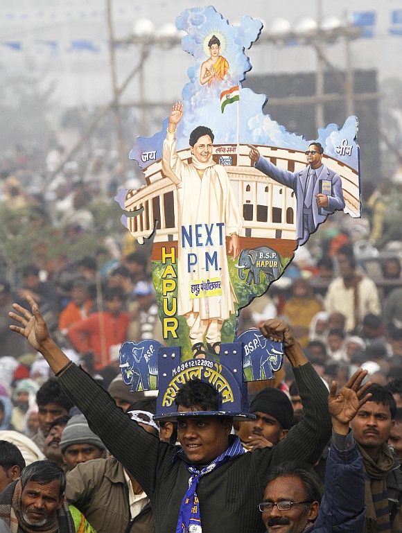 A BSP supporter with a cutout of a map of India with images of Mayawati and B R Ambedkar during an election rally