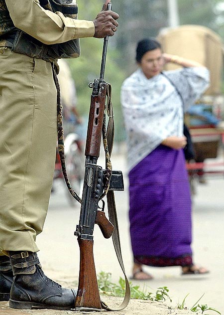 A paramilitary soldier stands guard beside a busy street in Manipur