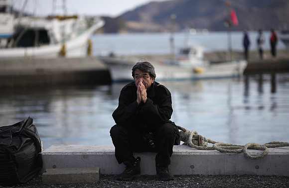 A man takes part in a moment of silence during a ceremony at an area damaged by March 11, 2011 earthquake and tsunami in Ofunato, Iwate Prefecture