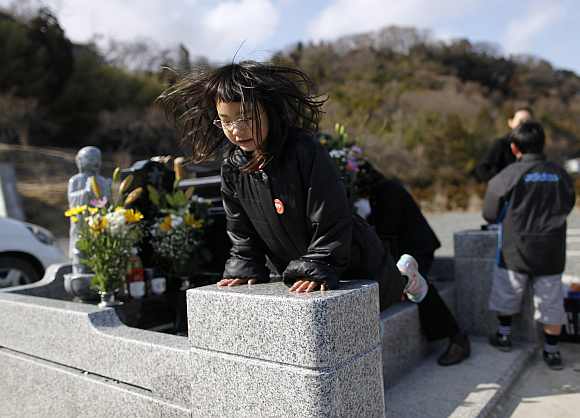 Wakana Kumagai, 7, jumps on the grave of her father, who was killed by the tsunami, in Higashimatsushima, Miyagi prefecture