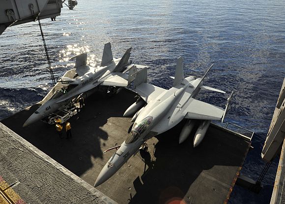 An F/A-18C Hornet assigned to the Thunderbolts of Marine Strike Fighter Squadron (VMFA) 251, left, and an F/A-18E Super Hornet assigned to the Knighthawks of Strike Fighter Squadron (VFA) 136 are lowered on an aircraft elevator to the hangar bay of the aircraft carrier USS Enterprise