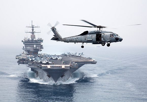 An HH-60H Sea Hawk helicopter, assigned to the Dragonslayers of Helicopter Anti-Submarine Squadron 11, flies in front of the aircraft carrier USS Enterprise as it transits the Strait of Bab el Mandeb