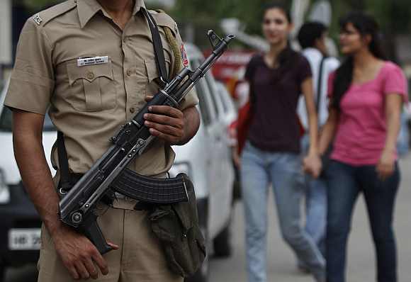A policeman stands guard as girls walk past outside a market in New Delhi