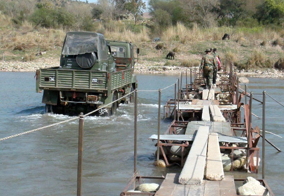 A river without a road bridge, where a big vehicle carries smaller vehicles across.