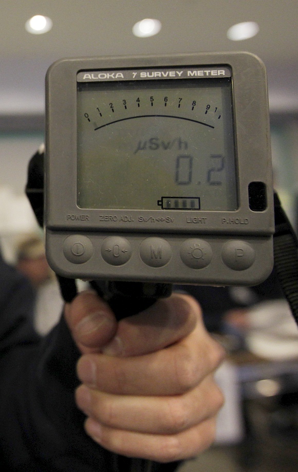 An employee of Yamagata city office holds a Geiger counter to detect radiation when evacuees from the vicinity of Fukushima nuclear plant wishe to be screened upon their arrival at an evacuation center set in a gymnasium in Yamagata, northern Japan