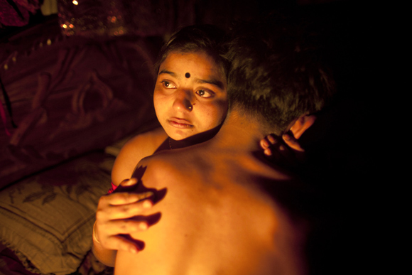 Seventeen-year-old prostitute Hashi, embraces a Babu, her 'husband', at a brothel house in Tangail, Bangladesh