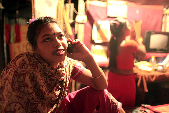 Sixteen-year-old Maya, a prostitute, talks on the phone inside her small room at Kandapara brothel in Tangail