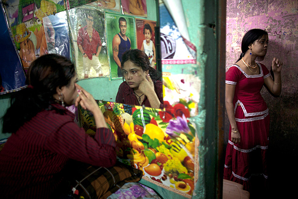 Prostitutes apply makeup as they try to attract customers inside a brothel in Faridpur