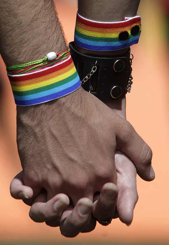 Two men hold hands as they attend a march against homophobia