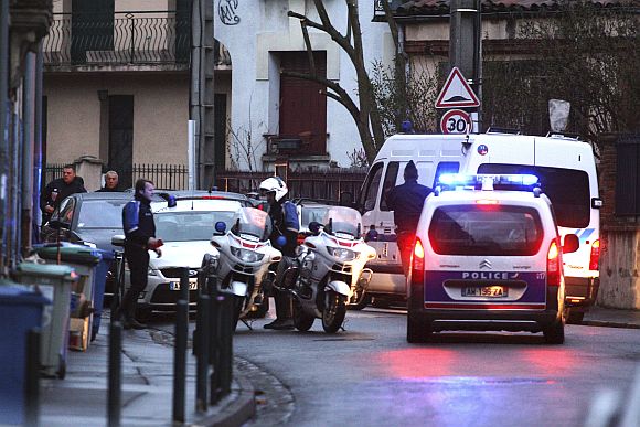 Masked French special intervention police (RAID) member arrives on the scene during a raid on a house to arrest the gunman