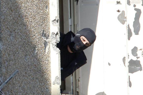 A masked French special unit policeman looks out of one of the window where special forces police staged the assault on the gunman Mohamed Merah, in Toulouse