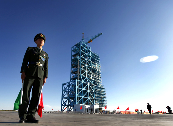 A Chinese soldier stands beside a Long March II-F rocket
