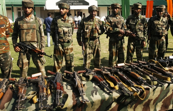 Army soldiers stand behind a display of seized arms and ammunition in Srinagar