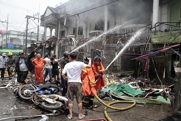 Thai rescue workers extinguish a fire at the site of a car bomb blast in southern Thailand's Yala province