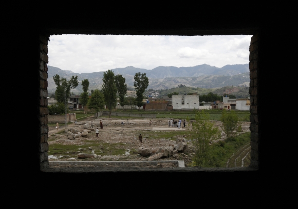 Children are seen through the window of a house under construction as they play cricket on the demolished site of a compound of Osama bin Laden in Abbottabad