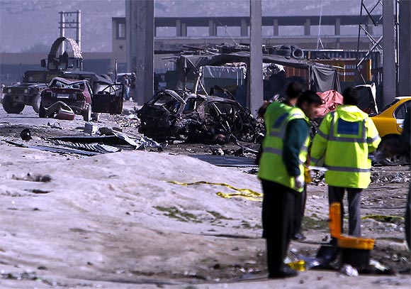 Afghan security forces members inspect the site of a car bomb attack in Kabul