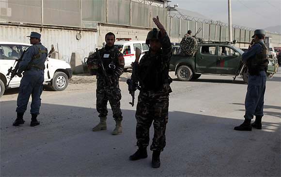 Afghan security forces members keep guard at the site of a car bomb attack