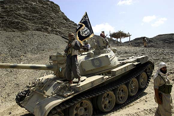Members of Ansar al-Sharia, an Al Qaeda-affiliated group, are seen near a tank taken from the army during recent battles, as they guard a road leading to the southern Yemeni town of Jaar