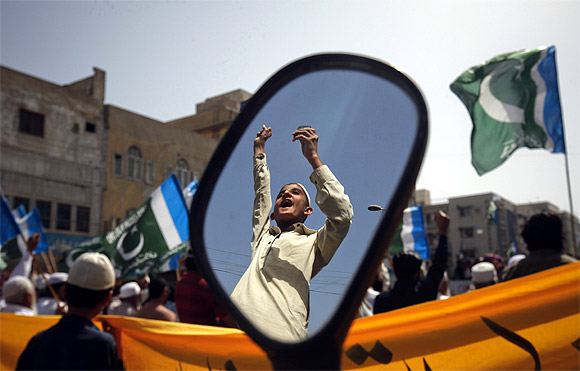 A supporter of the Jamaat-e-Islami is reflected in a mirror of a motorbike during an anti American and NATO demonstration in Karachi