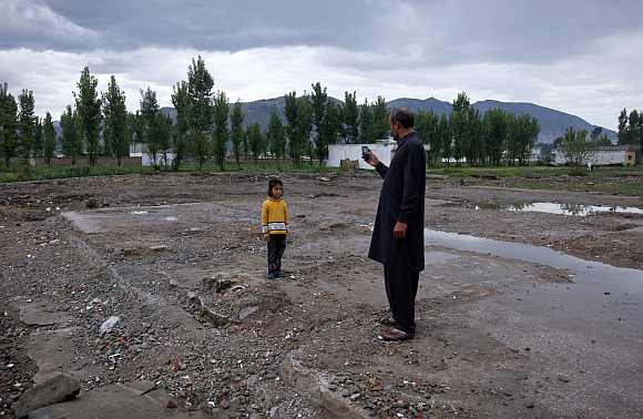 Six-year-old Anum, poses for her uncle for a picture while visiting the site of the demolished compound of Osama bin Laden