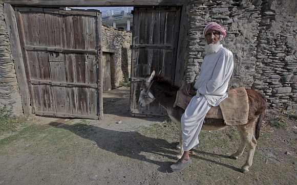 An elderly man rides a donkey along a road in the outskirt of Abbottabad