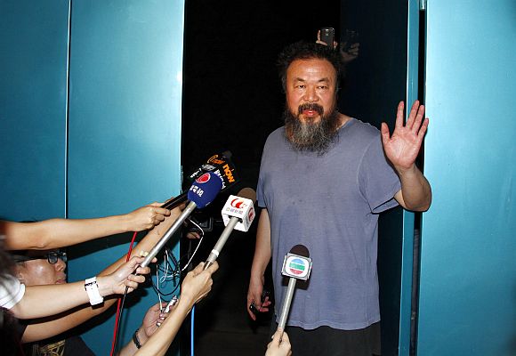 Dissident Chinese artist Ai Weiwei waves from the entrance of his studio after being released on bail in Beijing June 23, 2011