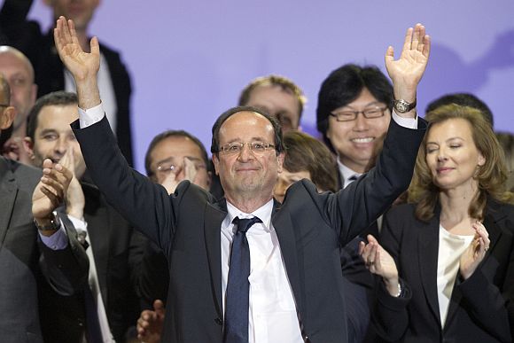 France's newly-elected President Francois Hollande celebrates on stage with his companion Valerie Trierweiler and Socialist party members during a victory rally at Place de la Bastille in Paris early May 7